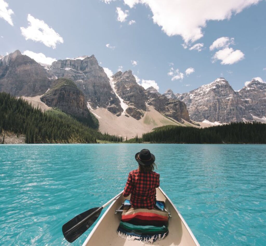 Traveler canoeing on turquoise Canadian lake symbolizing desire to extend stay in Canada